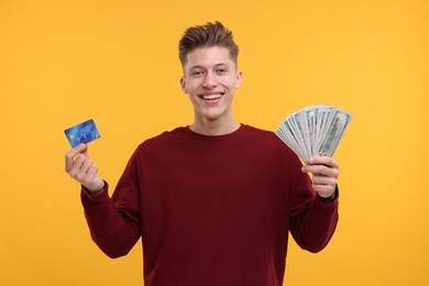 Photo of Happy man with dollar banknotes and credit card on yellow background