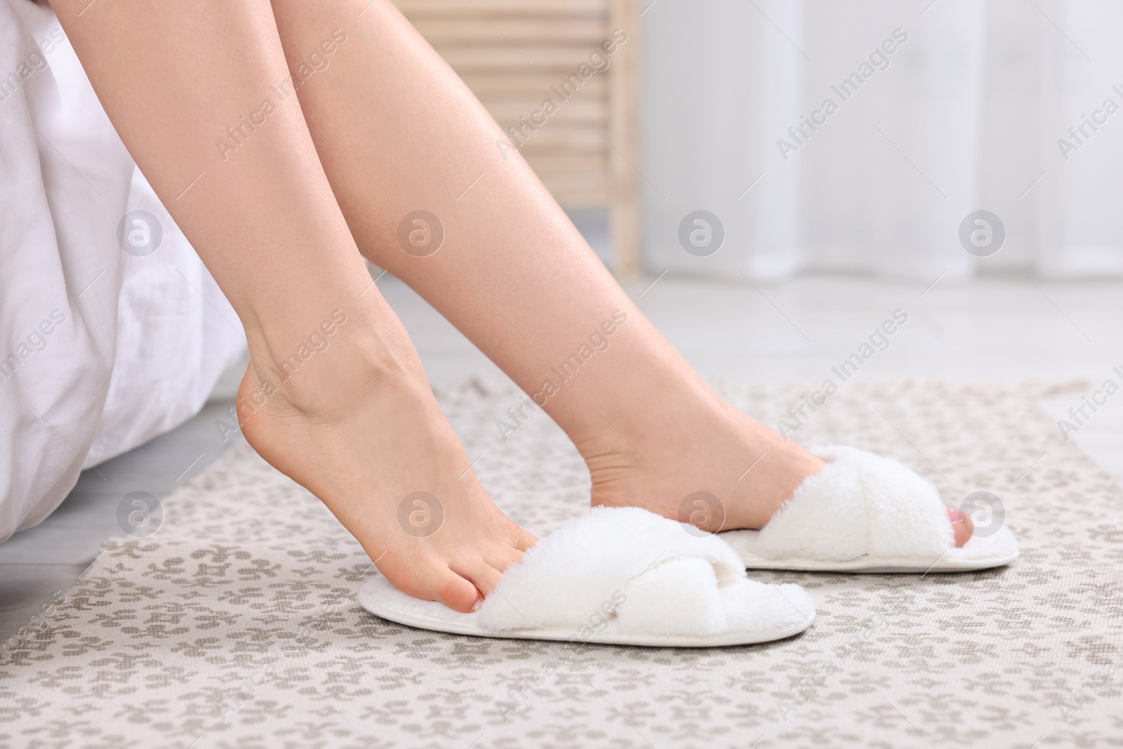 Photo of Woman wearing white soft slippers at home, closeup