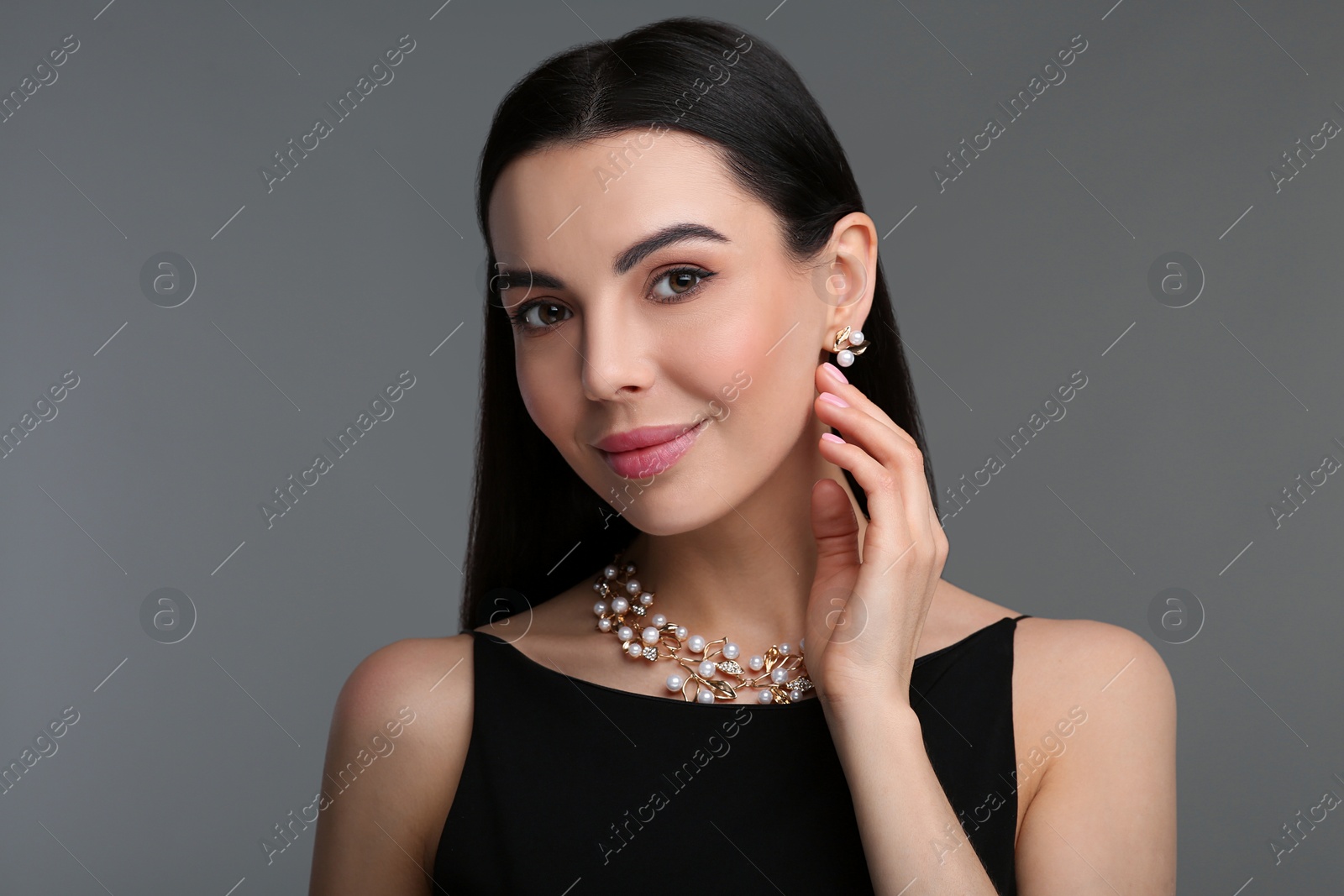 Photo of Beautiful young woman with elegant jewelry on dark grey background