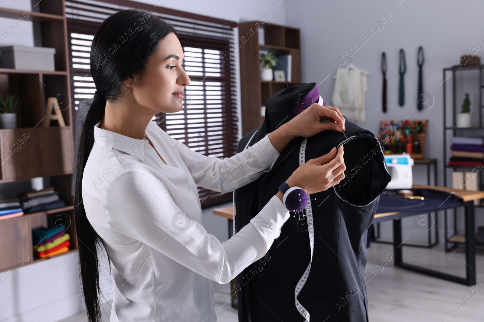 Photo of Professional dressmaker making suit jacket in atelier