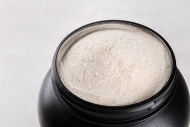 Photo of Black jar full of protein powder on light background, closeup