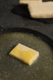 Photo of Melting butter in frying pan on grey table, closeup