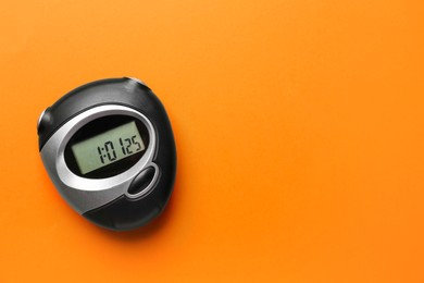 Digital timer on orange background, top view. Space for text