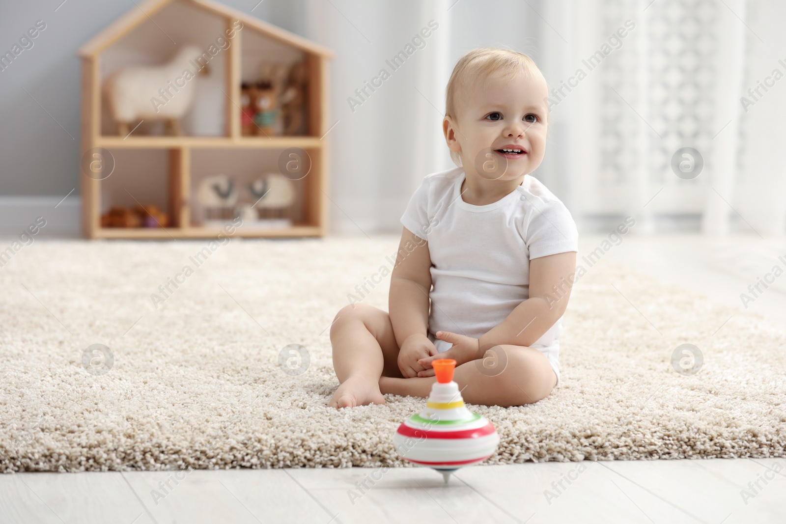 Photo of Children toys. Cute little boy and spinning top on rug at home