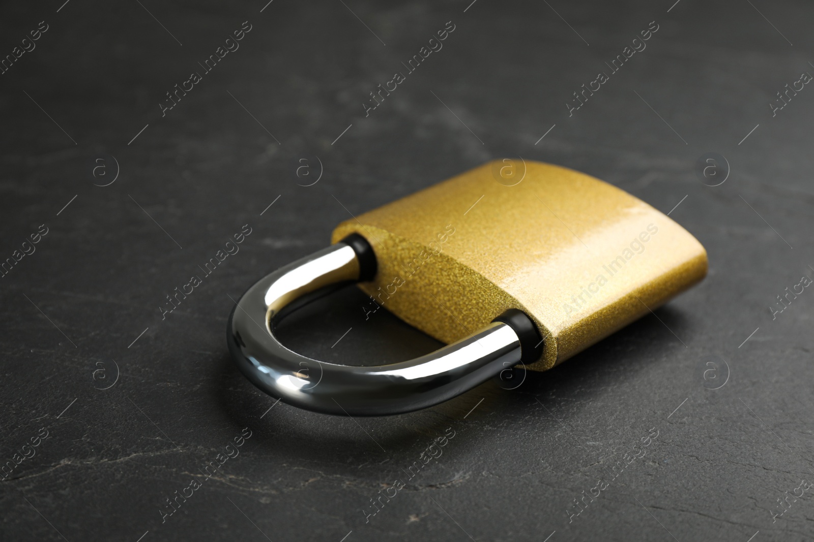 Photo of Modern padlock on black table, closeup. Safety and protection