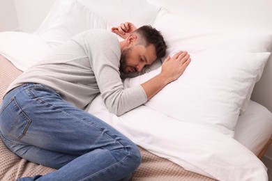 Photo of Upset man lying on bed. Loneliness concept