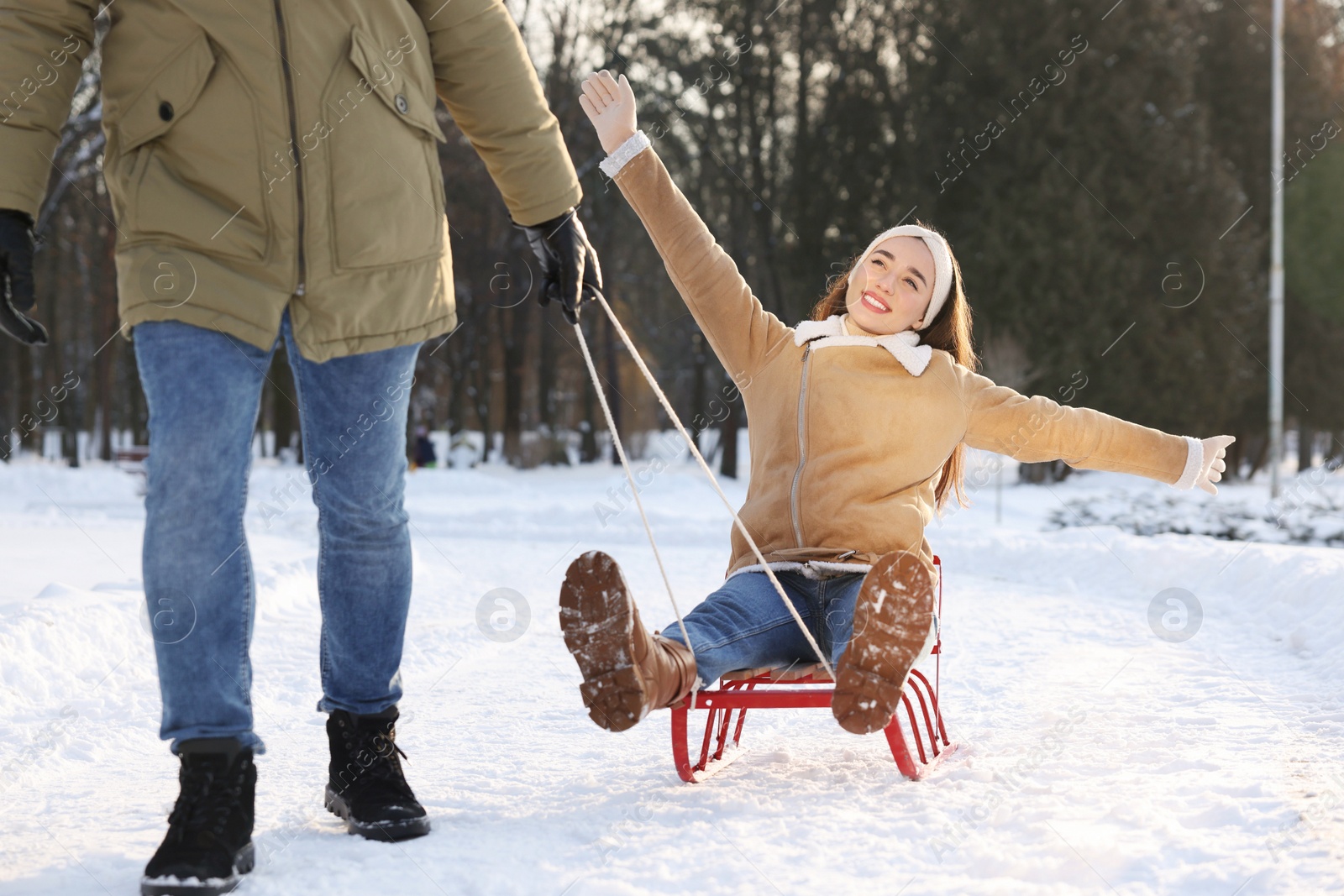 Photo of Man pulling his girlfriend in sleigh outdoors on winter day