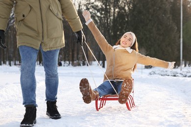 Man pulling his girlfriend in sleigh outdoors on winter day