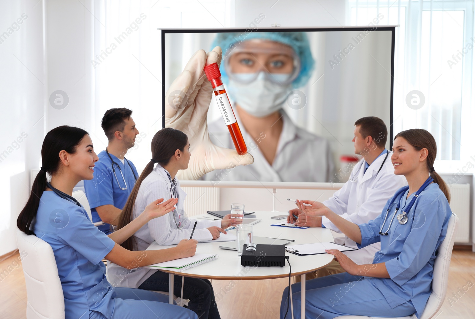 Image of Team of doctors using video projector during coronavirus conference in office