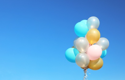 Photo of Colorful balloons against clear blue sky on sunny day. Space for text