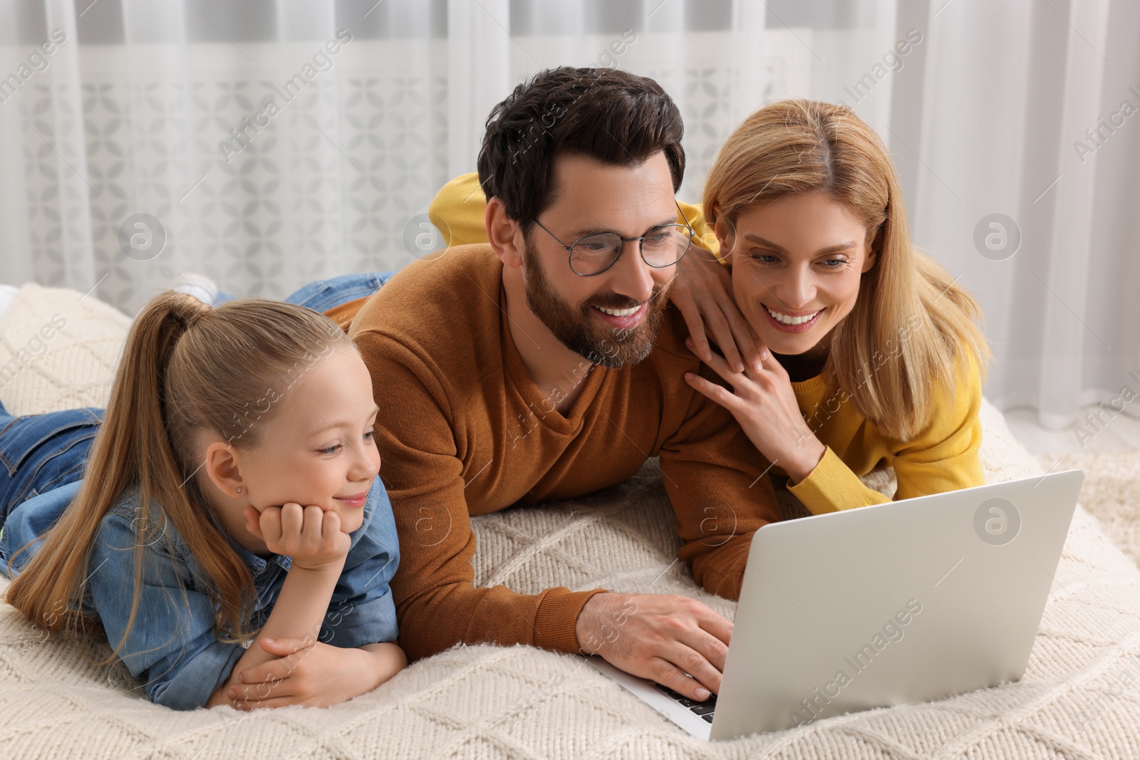 Photo of Happy family with laptop on bed at home