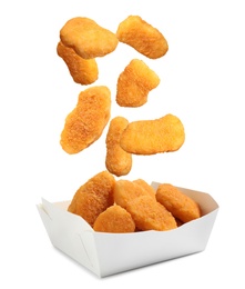 Fresh chicken nuggets falling into container on white background