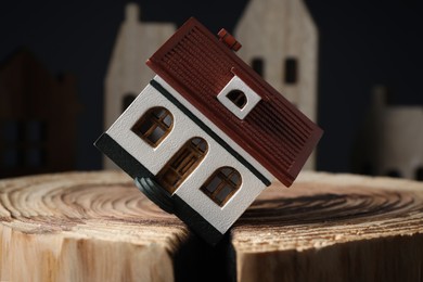 Photo of House model in cracked wooden stump depicting earthquake disaster, closeup