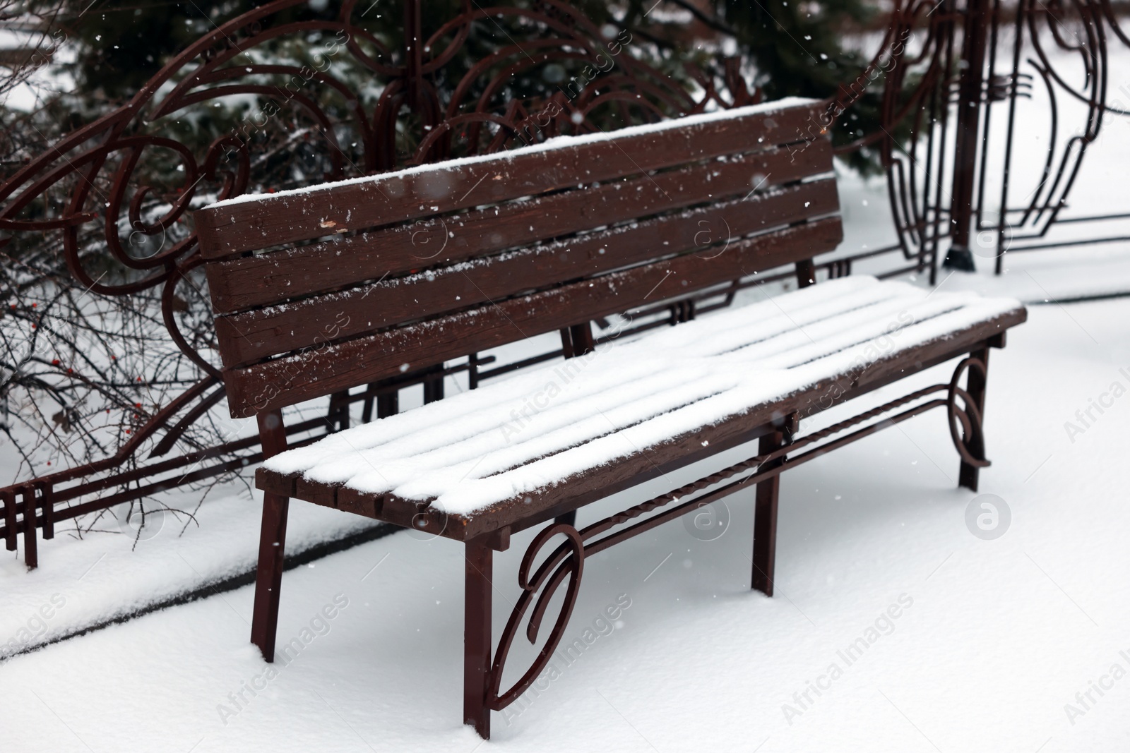 Photo of Bench covered with snow in city park