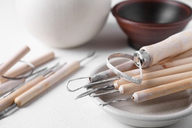 Photo of Set of different clay crafting tools on white table, closeup