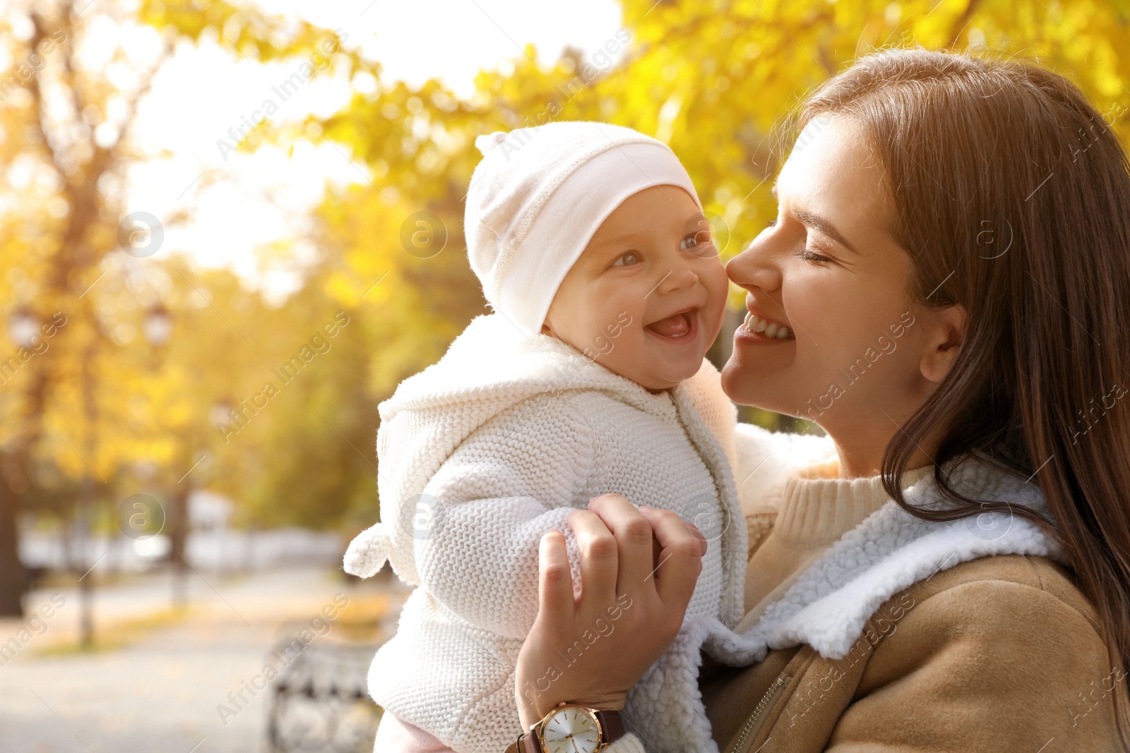 Photo of Happy mother with her baby daughter in park on autumn day, space for text