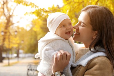 Photo of Happy mother with her baby daughter in park on autumn day, space for text
