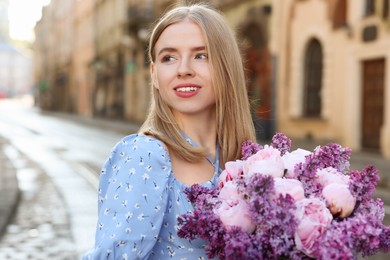 Beautiful woman with bouquet of spring flowers on city street