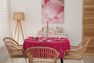 Photo of Beautiful table setting with green branches and burning candles in dining room