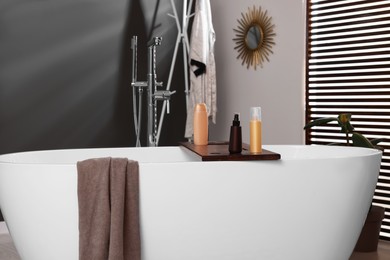 Stylish bathroom interior with ceramic tub and cosmetic products