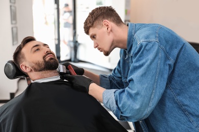 Photo of Professional barber working with client in hairdressing salon. Hipster fashion