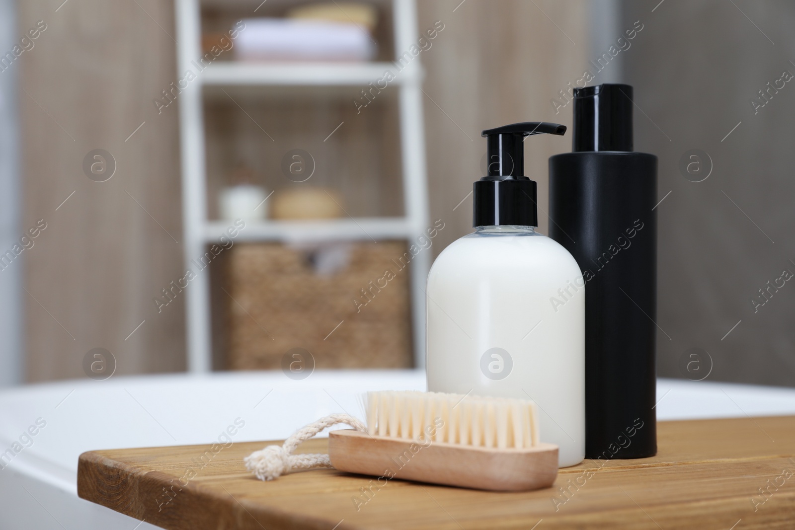 Photo of Wooden bath tray with bottles of shower gels and brush on tub indoors, space for text