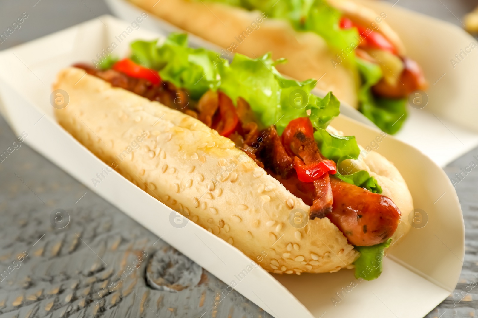 Photo of Hot dogs on grey wooden table, closeup. Fast food