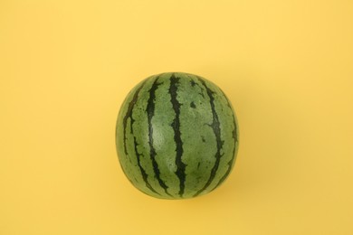 Photo of One whole ripe watermelon on yellow background, top view
