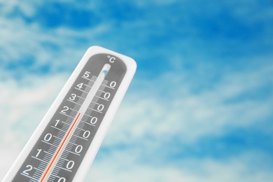 Weather thermometer and blue cloudy sky on background. Space for text