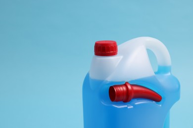 Photo of Plastic canister with color liquid on light blue background, closeup. Space for text