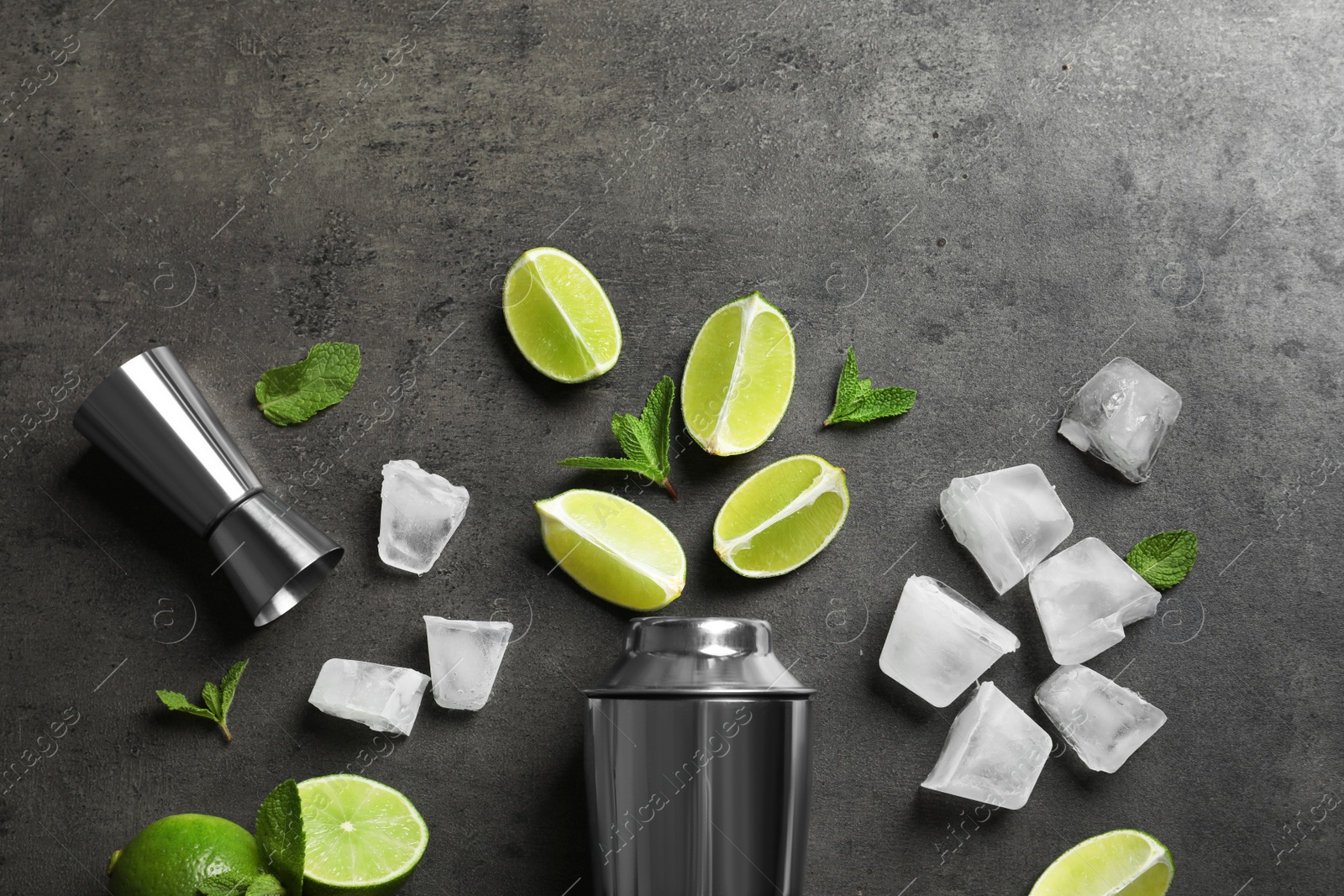 Photo of Flat lay composition with lime, mint and shaker on grey background. Refreshing beverage ingredients