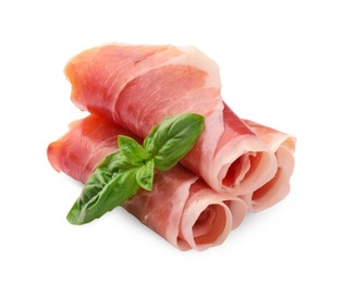 Photo of Rolled slices of delicious jamon and basil leaves isolated on white