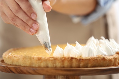 Woman preparing lemon meringue pie, closeup view