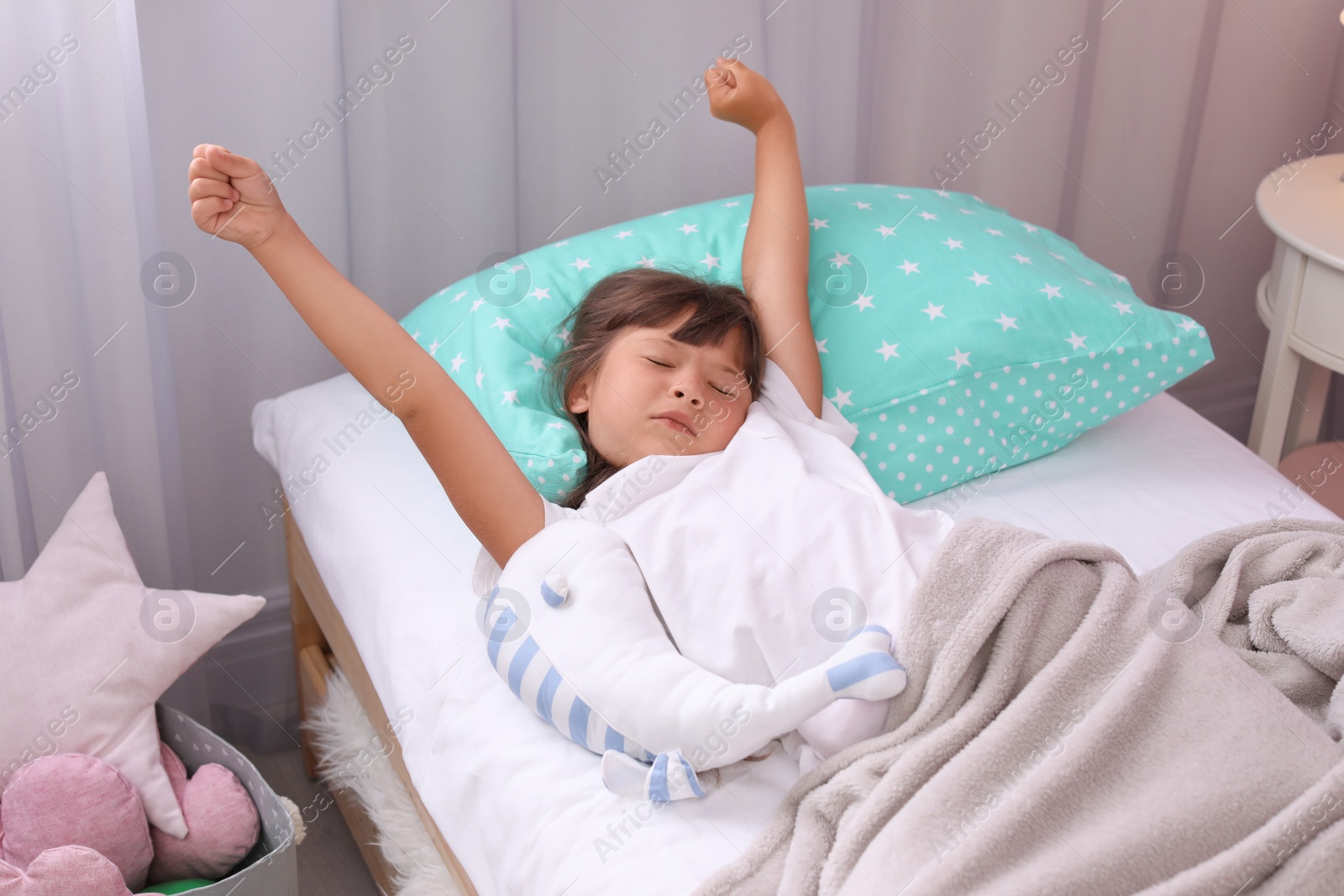 Photo of Little girl stretching in bed at home. Time to sleep