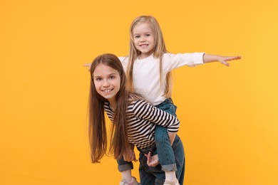 Portrait of cute little sisters on orange background