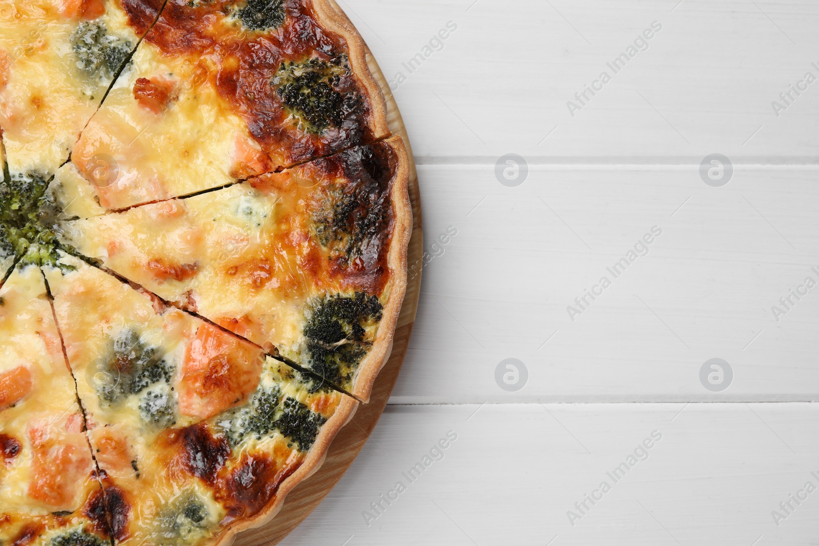 Photo of Delicious homemade quiche with salmon and broccoli on white wooden table, top view. Space for text