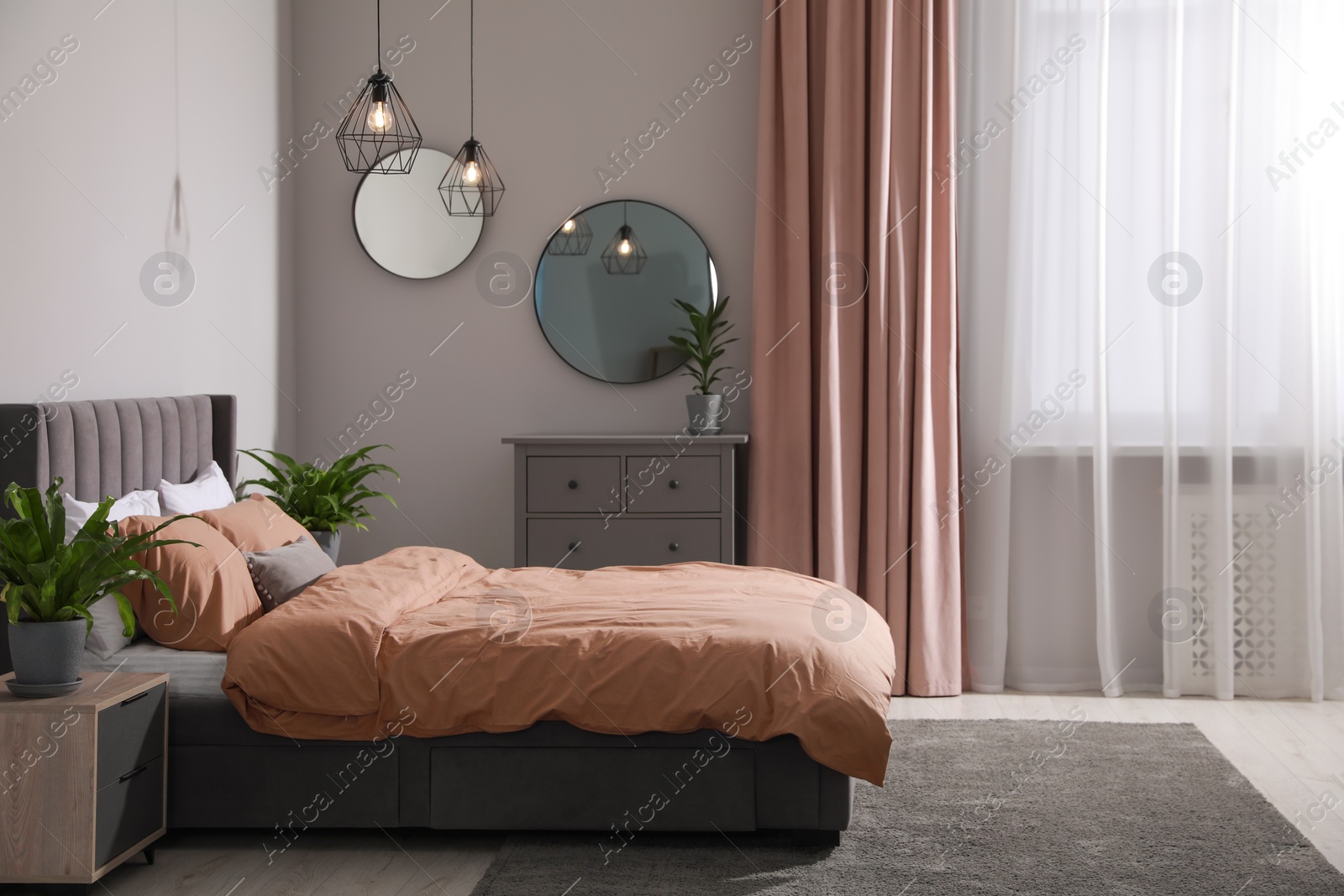 Photo of Stylish bedroom interior with comfortable bed and green houseplants