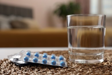 Glass of water and pills on wicker mat indoors, closeup with space for text. Potency problem concept