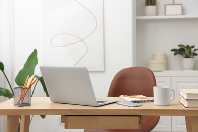 Photo of Home office. Stylish workplace with laptop and stationery on wooden desk indoors