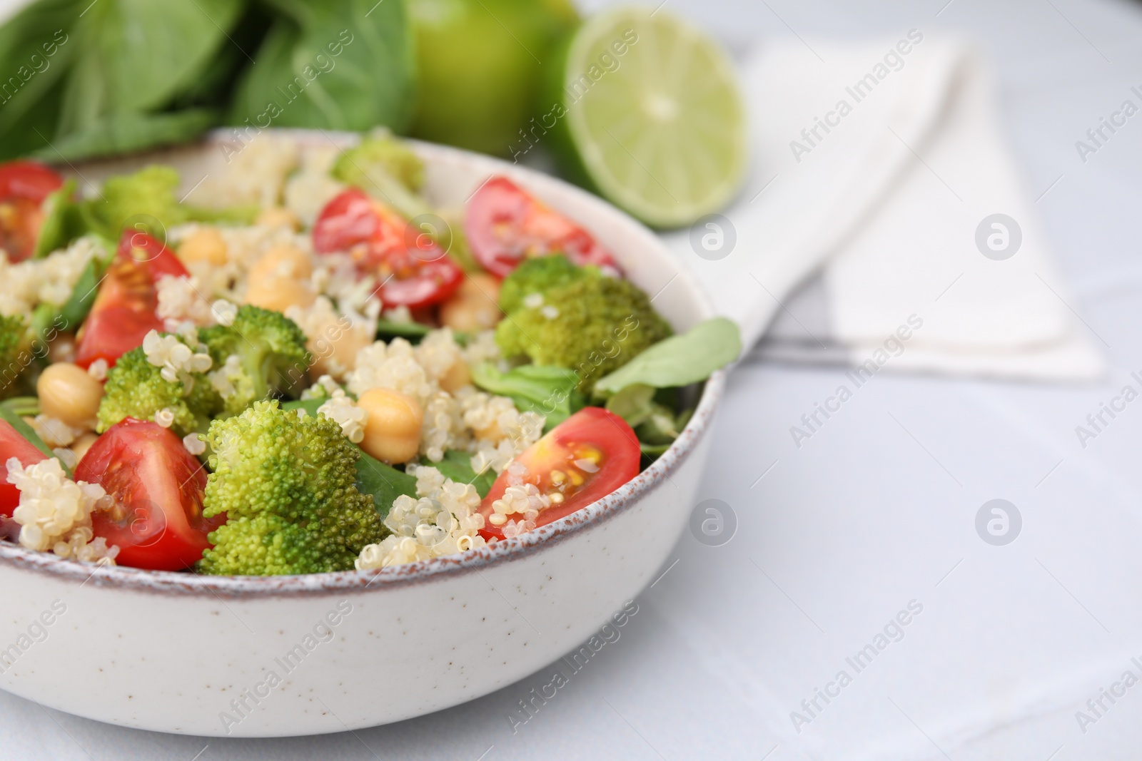 Photo of Healthy meal. Tasty salad with quinoa, chickpeas and vegetables on white table, closeup with space for text