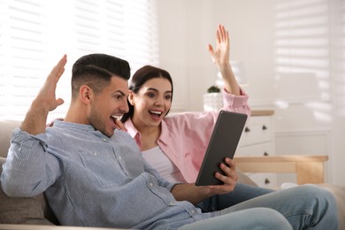 Photo of Emotional couple participating in online auction using tablet at home
