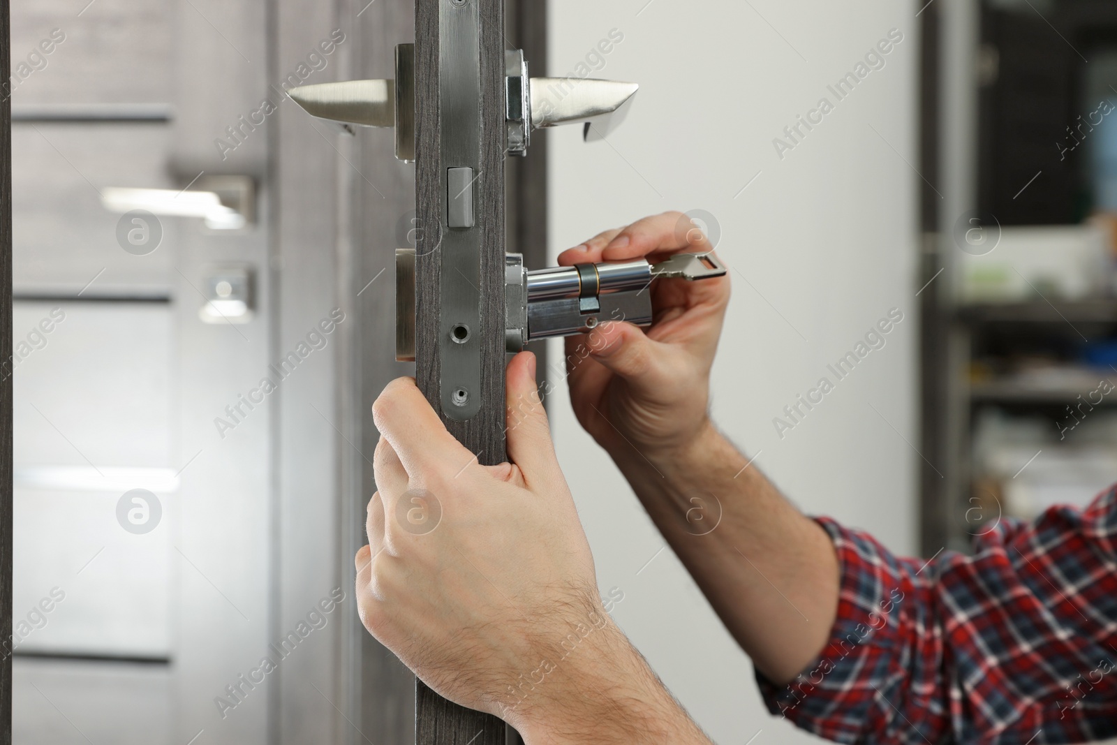 Photo of Handyman changing core of door lock indoors, closeup