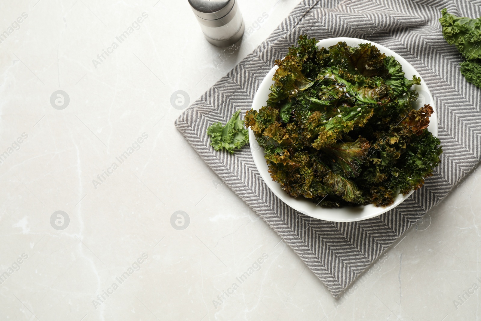 Photo of Tasty baked kale chips on grey marble table, flat lay. Space for text