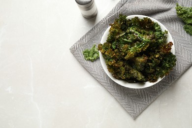 Photo of Tasty baked kale chips on grey marble table, flat lay. Space for text