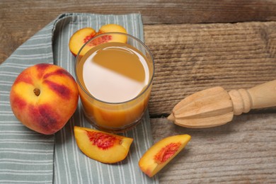 Photo of Glass of peach juice, fresh fruits and citrus reamer on wooden table, above view