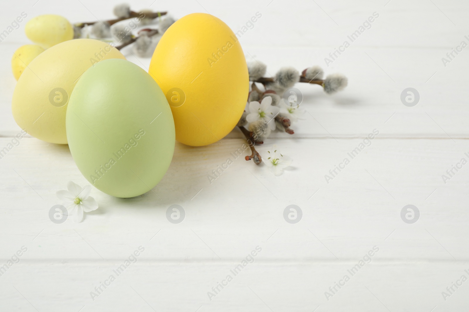 Photo of Colorful Easter eggs on white wooden table. Space for text