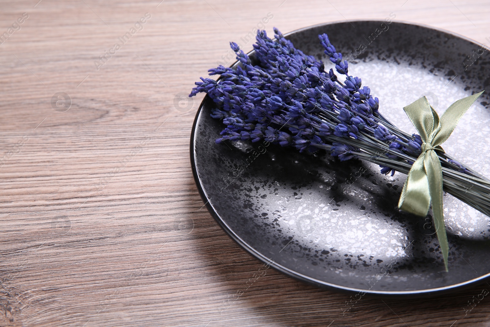 Photo of Bouquet of beautiful preserved lavender flowers and plate on wooden table, space for text