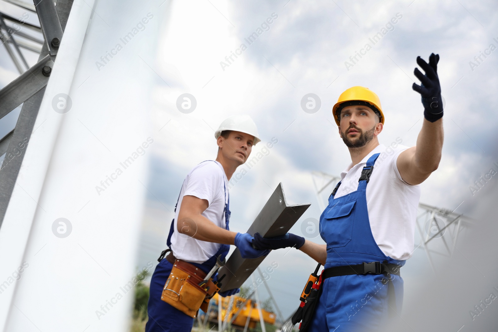 Photo of Workers building high voltage tower construction outdoors. Installation of electrical substation