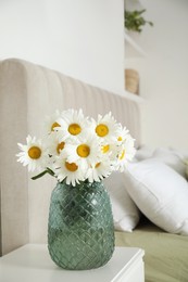 Bouquet of beautiful daisy flowers on nightstand in bedroom