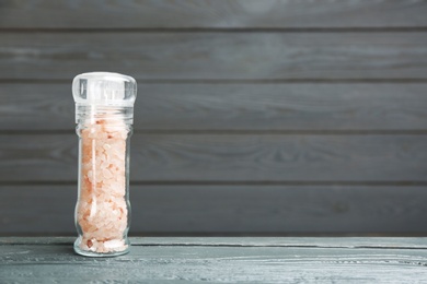 Photo of Grinder with pink himalayan salt on wooden table, space for text